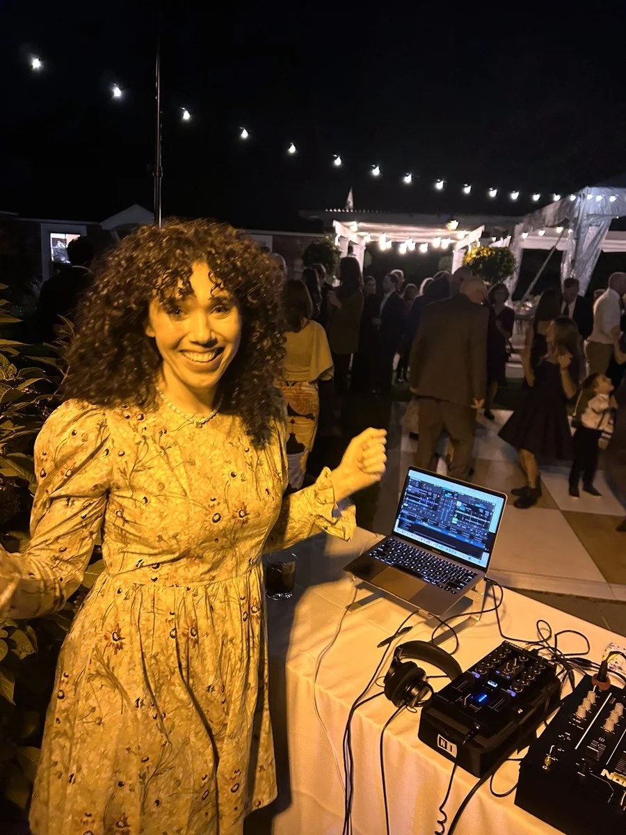Olivia Bradley-Skill DJing a wedding, focused on her equipment while keeping the dance floor energized.