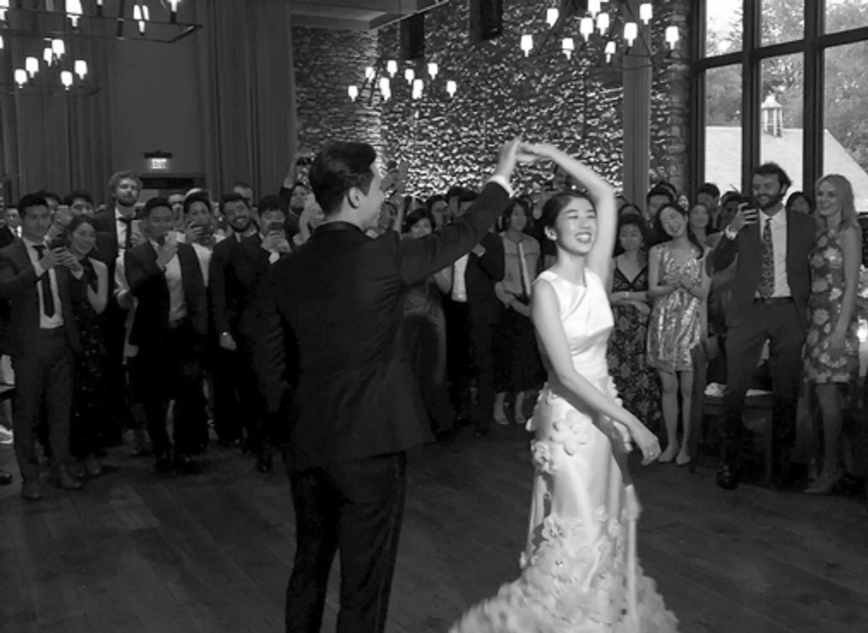 nyc Blue Hill at Stone Barns non traditional wedding dj: Black-and-white wedding dance with groom twirling smiling bride as guests watch and clap in a chandelier-lit ballroom.