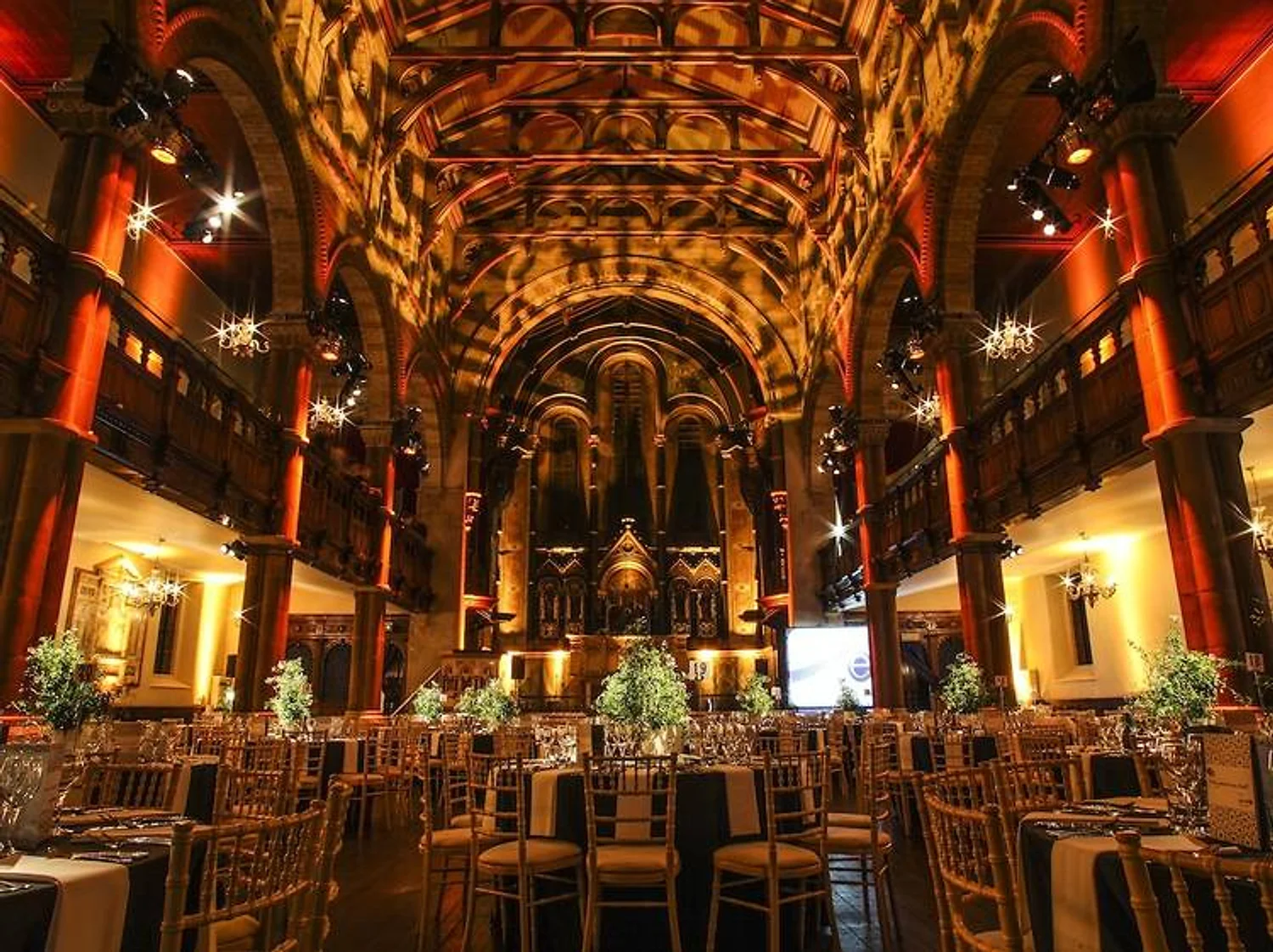 NYC wedding DJ Angel Orensanz Foundation glowing orange, with set tables and gold chairs under arched ceilings and chandeliers.