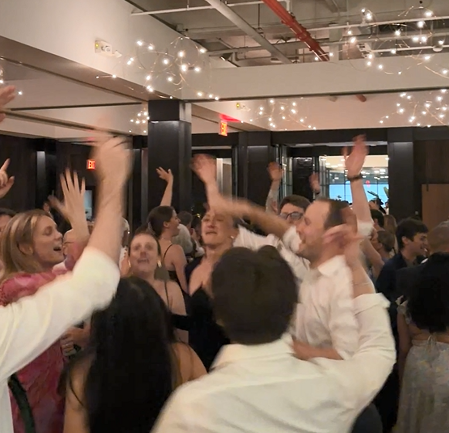 nyc non traditional wedding dj brooklyn winery Bride and groom dance with cheering guests at a lively wedding reception in a warmly lit room.