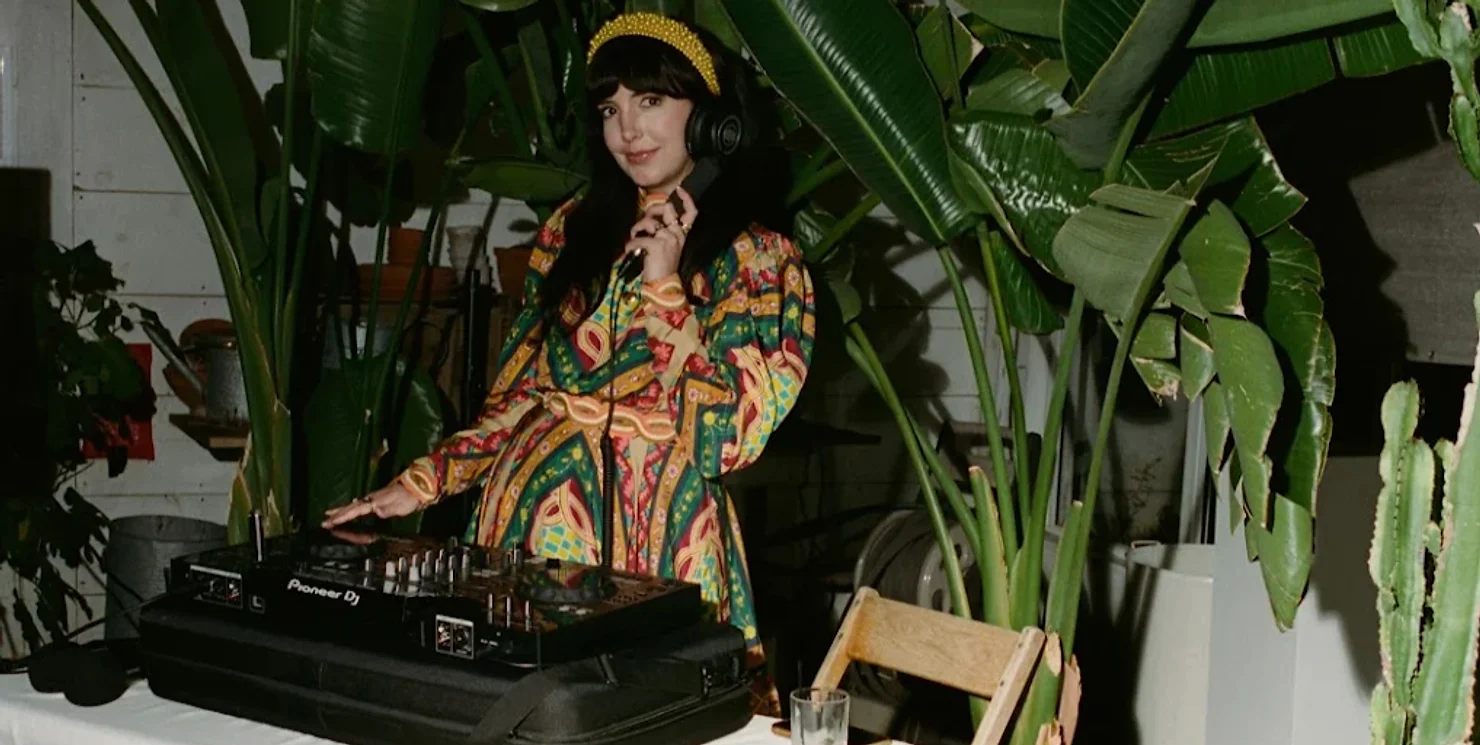 NYC Wedding DJ performing at a botanical-themed event with professional Pioneer DJ gear and tropical decor.
