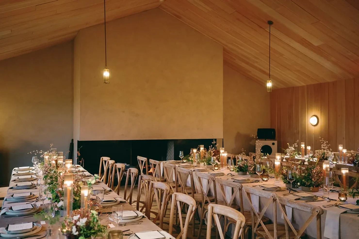 nyc ulster county wedding dj Warmly lit banquet hall with long candlelit tables, floral centerpieces, and wooden chairs under a vaulted wood ceiling