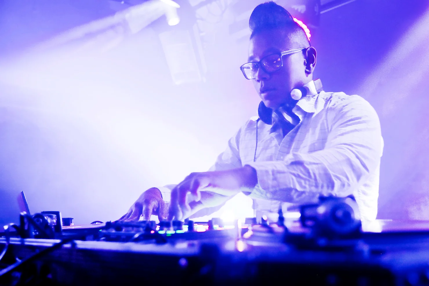 nyc non traditional wedding djs with Live Musicians DJ with glasses and headphones mixing music at turntables under purple-blue club lights