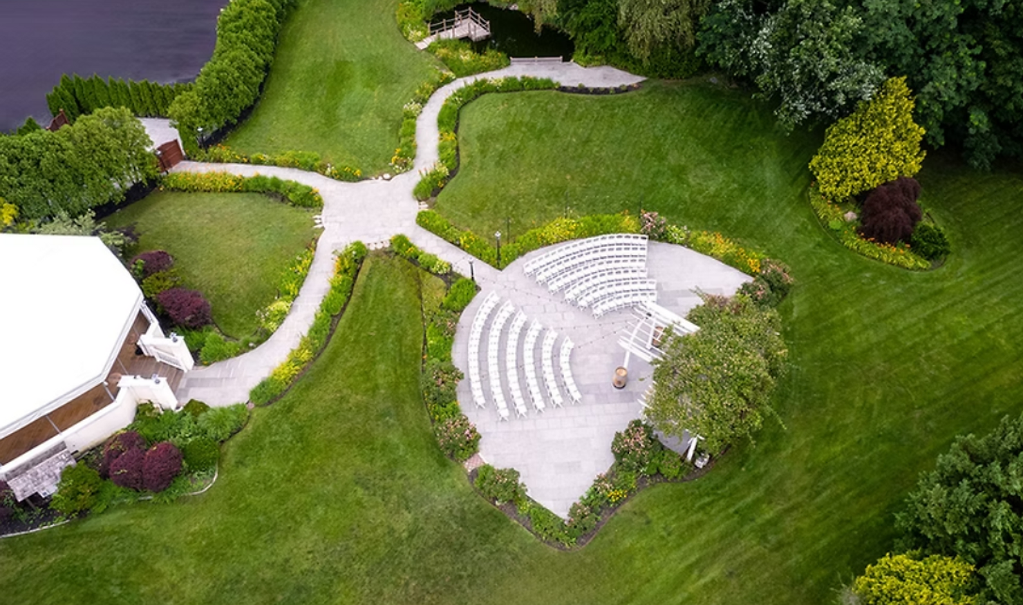 NYC wedding DJ Aerial view of a landscaped garden with white semicircular amphitheater seating, winding paths, lawns, and a small building