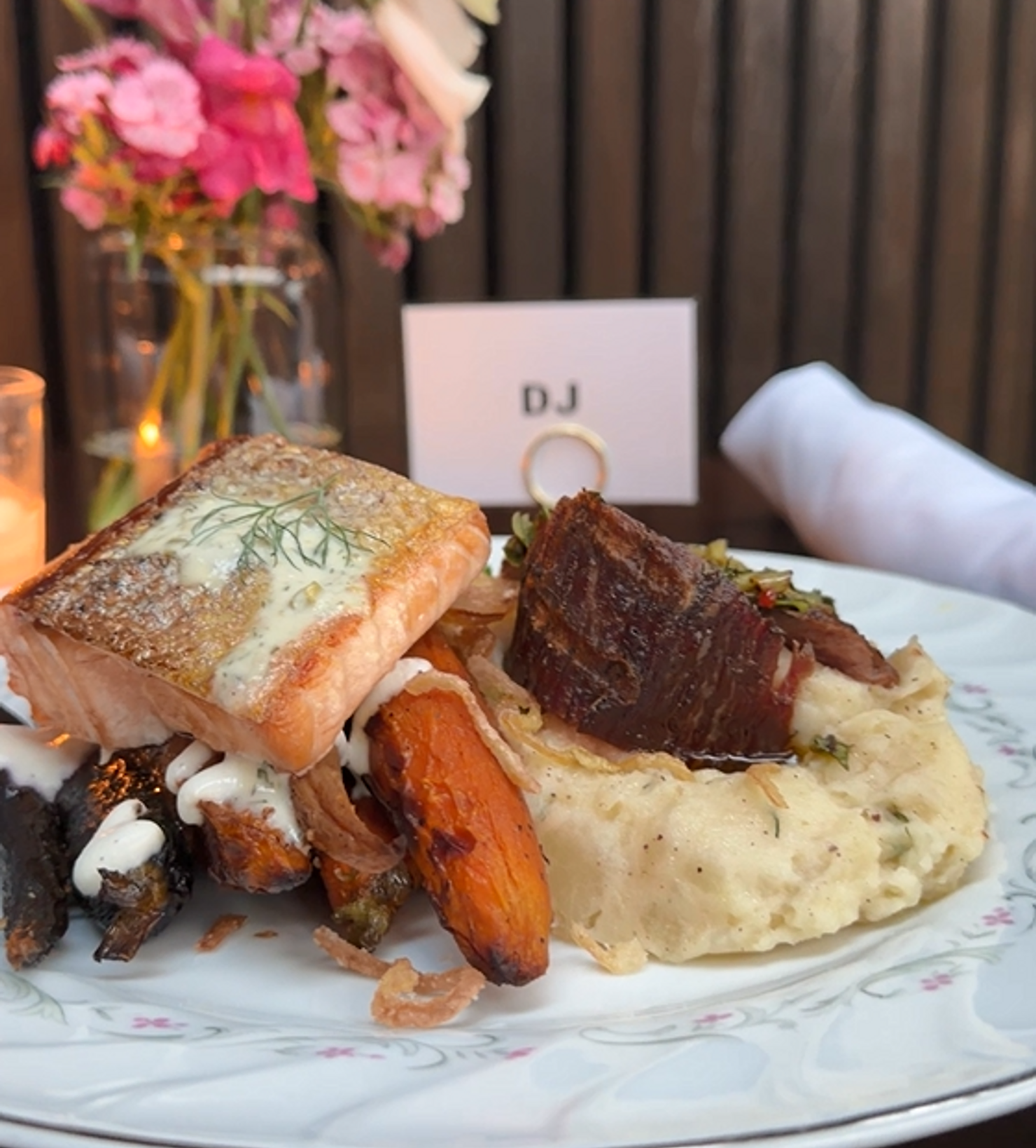 nyc non traditional wedding dj brooklyn winery Plated salmon, beef and roasted vegetables on mashed potatoes at a table with flowers and a DJ sign in the background.