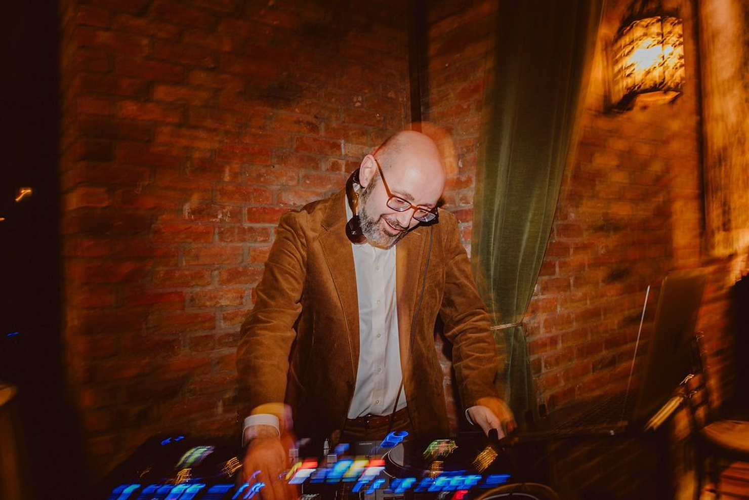 Wedding DJ mixing tracks live on controller during reception at brick venue