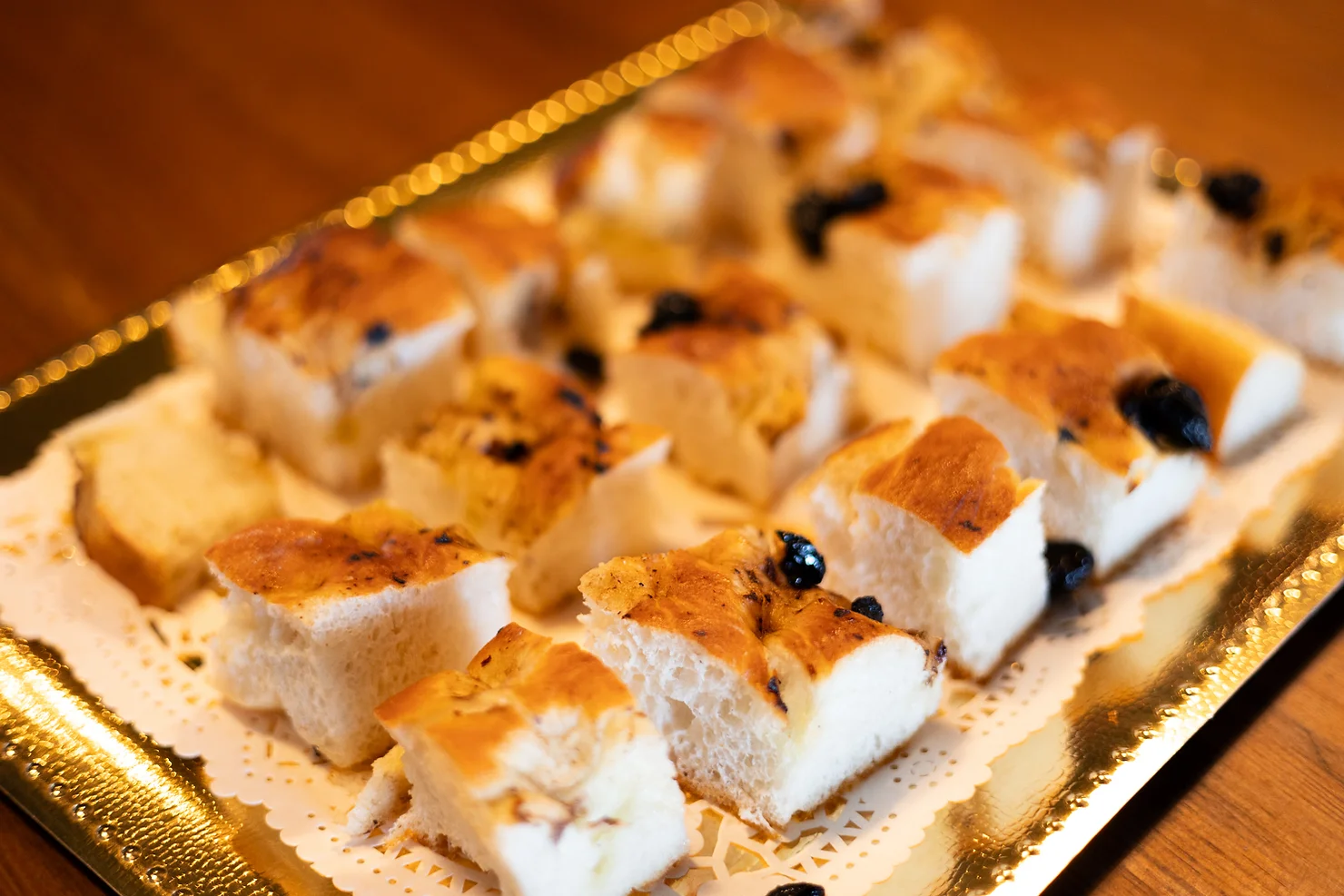 NYC wedding DJ Strong Rope Brewery Golden tray of sliced raisin bread or cake on a doily, warmly lit on a wooden table